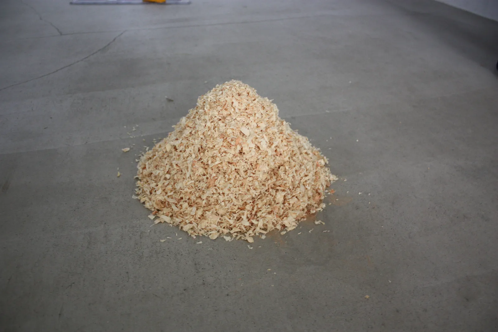 A pile of wood shavings on a concrete floor