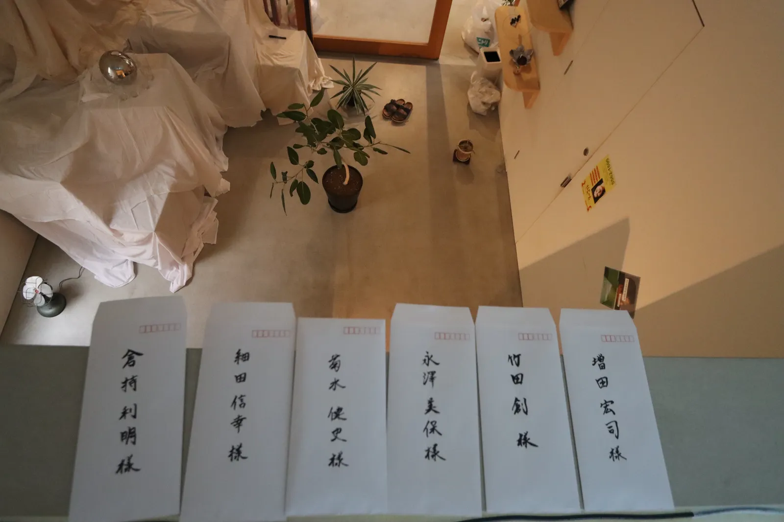 Handwritten envelopes in front of an overhead photograph of a room