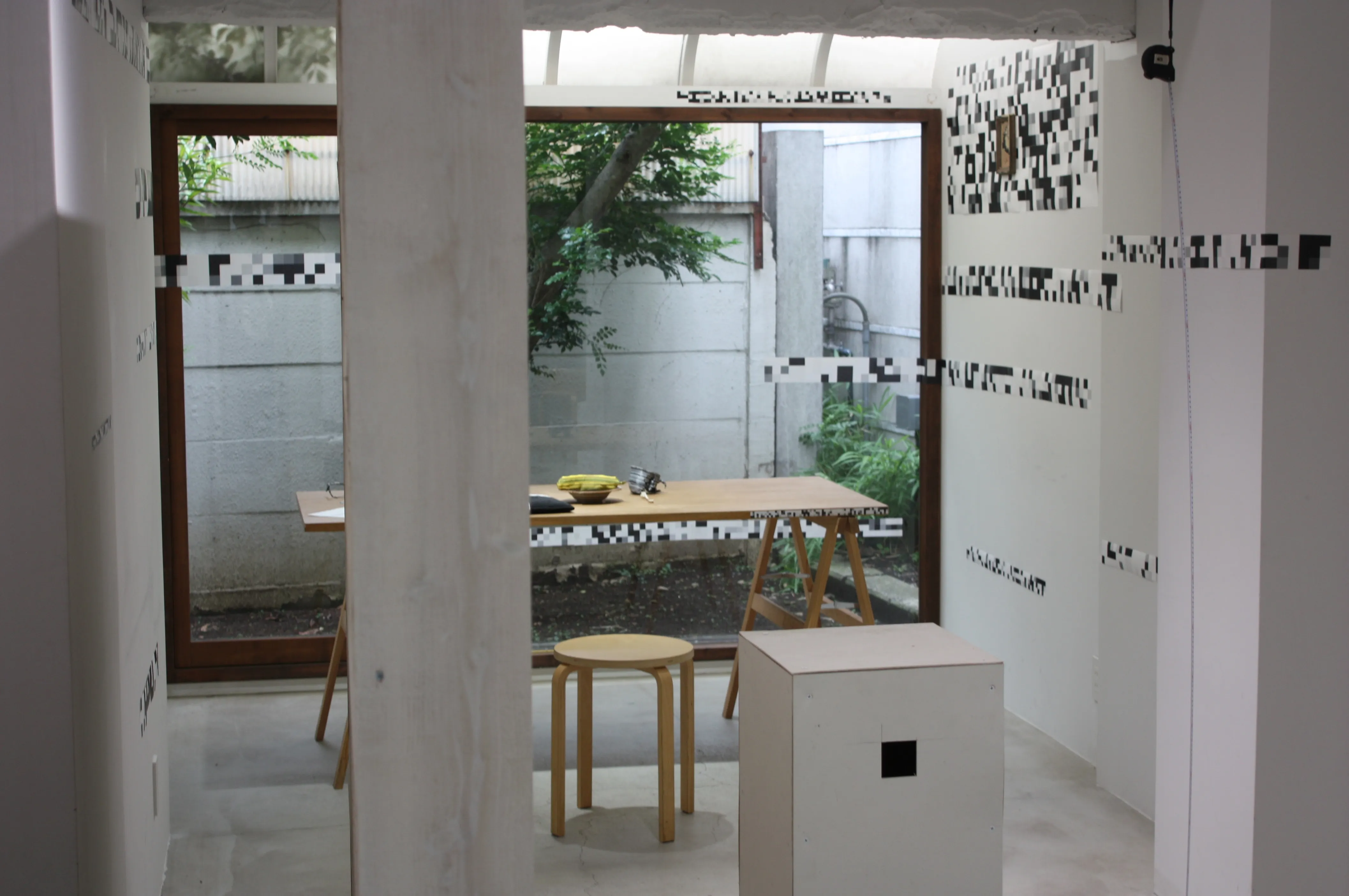REAL_copy installation room with a wooden box, table, chair, and black-and-white wall markings