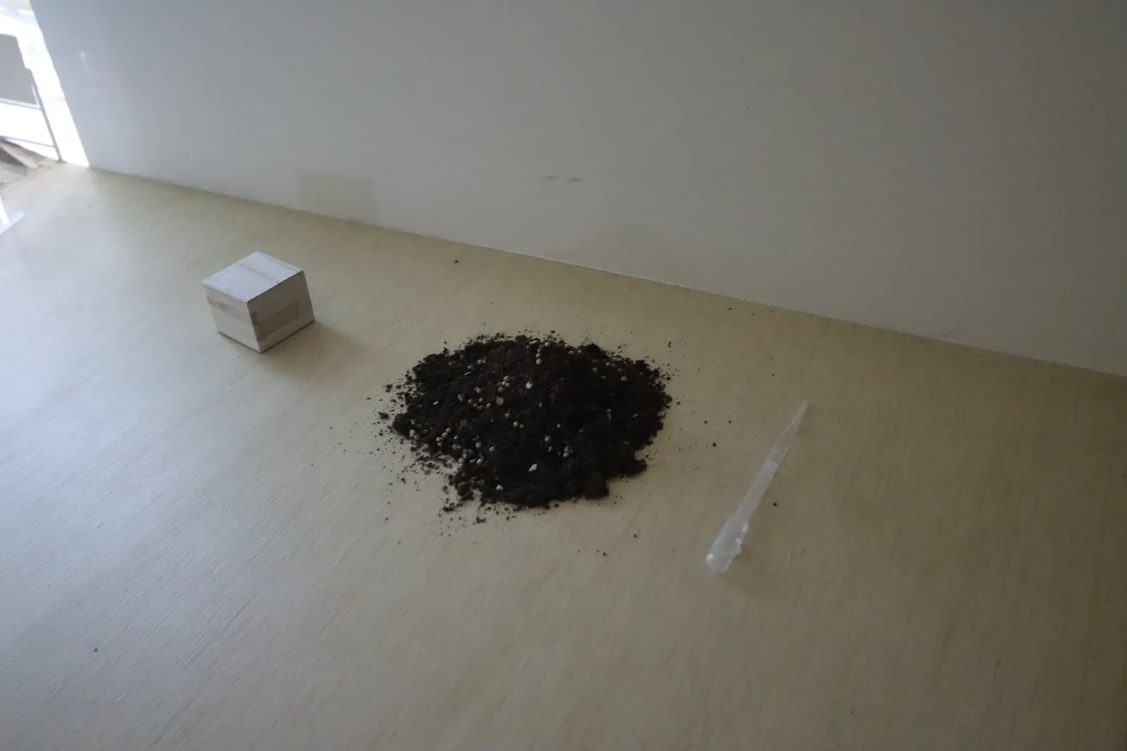 A pile of soil on the floor beside a small box
